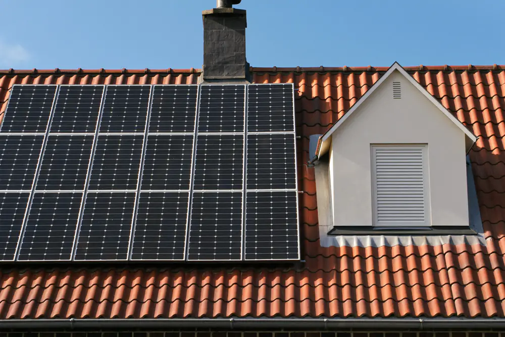 Dak met zwarte zonnepanelen naast een witte dakkapel