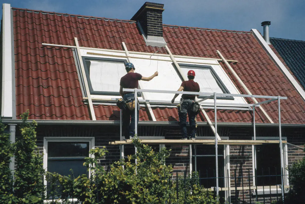 Twee timmerlieden voor een net geplaatste witte dakkapel op een achterdakvlak