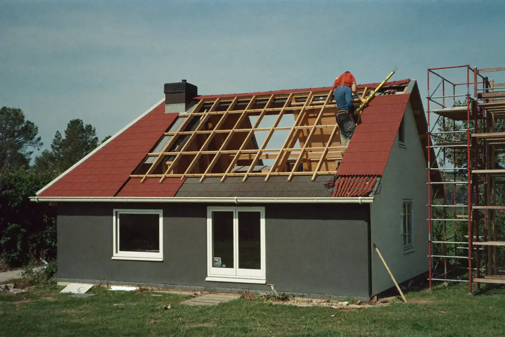 Een timmerman bouwt het houten geraamte van een traditionele dakkapel op het dak