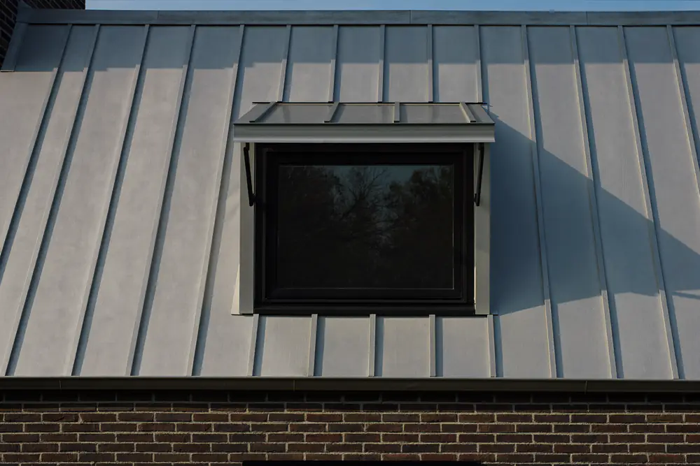 Dakkapel bekleed met grijs zink met strakke lijnen op een bakstenen woning
